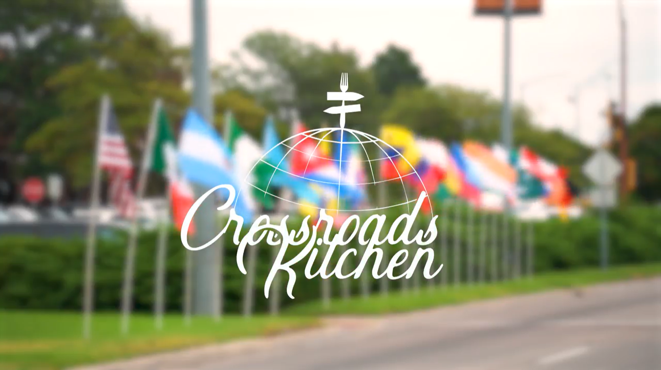 White Crossroads Kitchen logo on top of an image of a blurred flag display